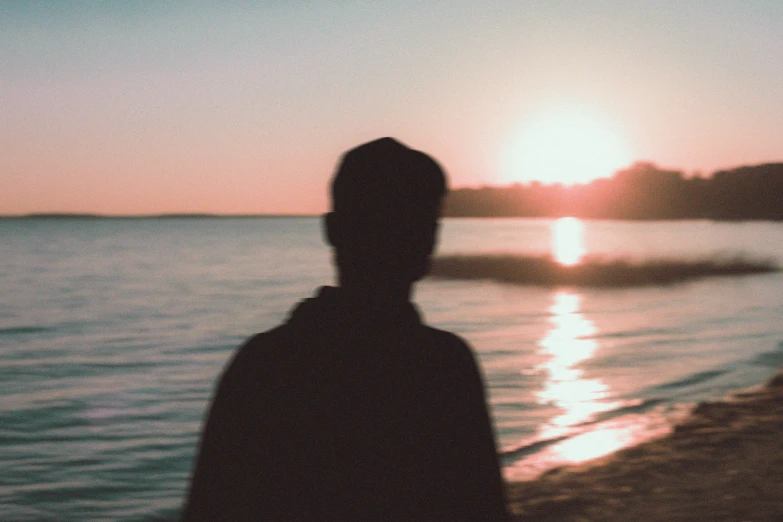 a person standing on a beach by the water at sunset