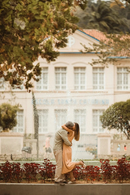 the kissing couple is in front of the building and trees