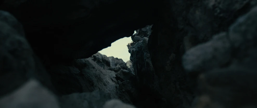 a man stands at the top of a rocky cliff