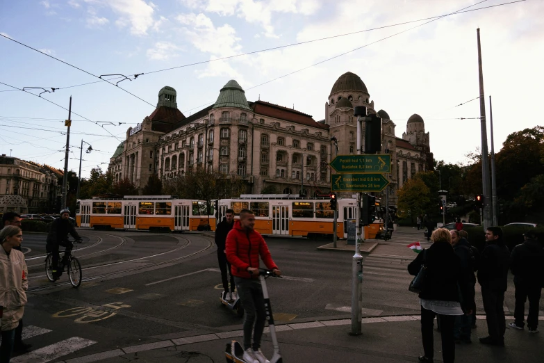 several pedestrians walk across a street as a yellow bus passes