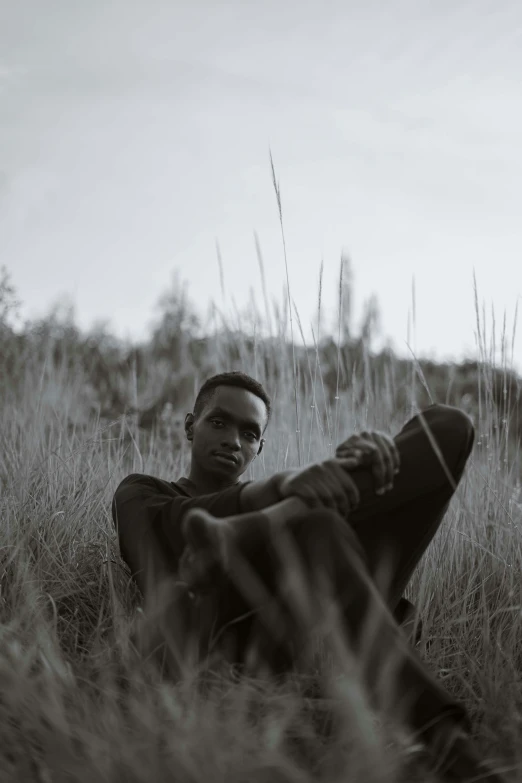 a man sits in a grassy area wearing sunglasses