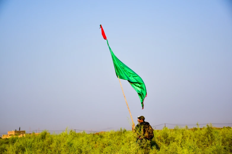 a man is walking through tall grass with a kite