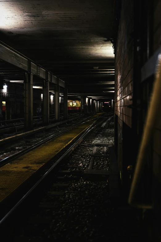 the train tracks in an empty subway station are dark