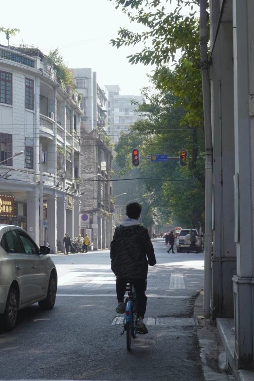 an asian man on his bicycle going through the crosswalk