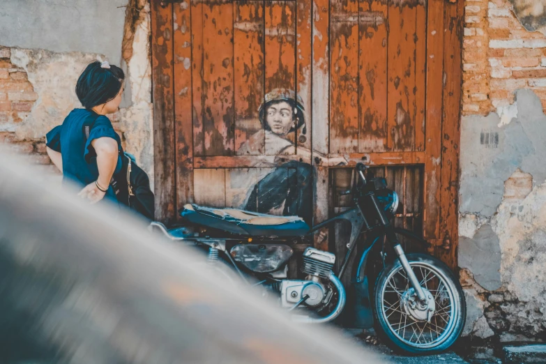 a woman sitting on a motorcycle and painting a woman's face