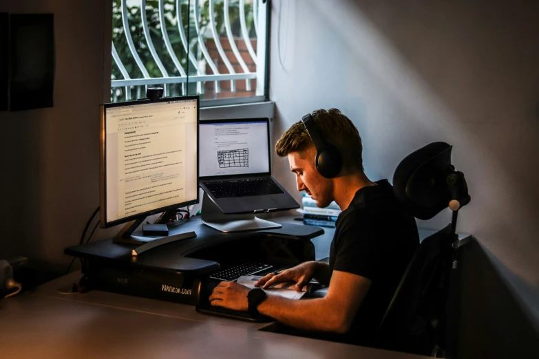 a man sitting at a desk with his headphones up in front of him