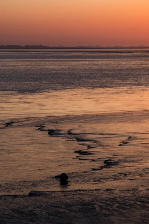 the sunset and a body of water with some small waves in it