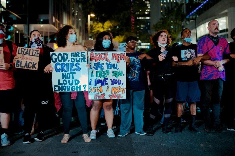 a group of people standing on the side walk holding signs