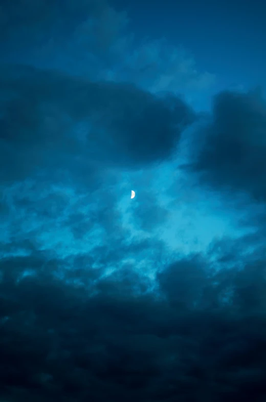 a full moon sits above some blue clouds