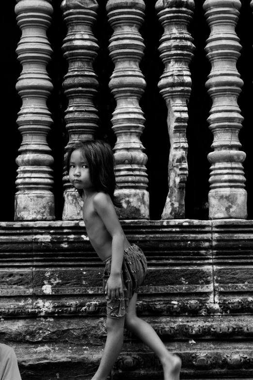 two children standing outside in front of large columns