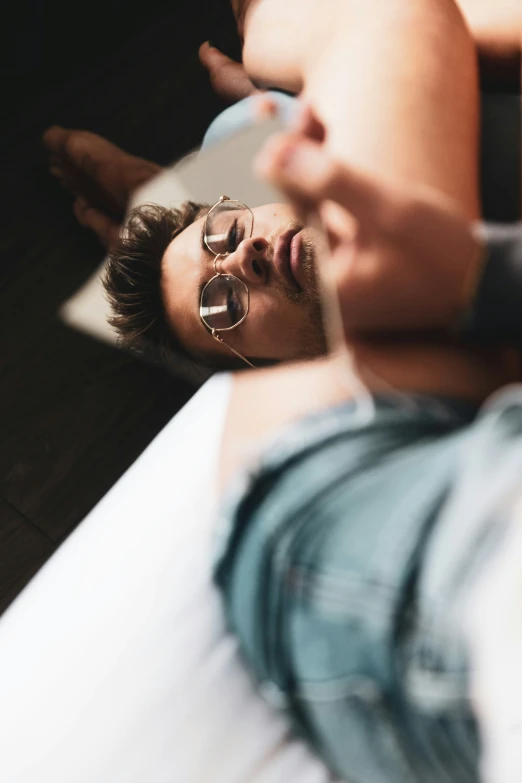 an image of a man with glasses on laying on the bed