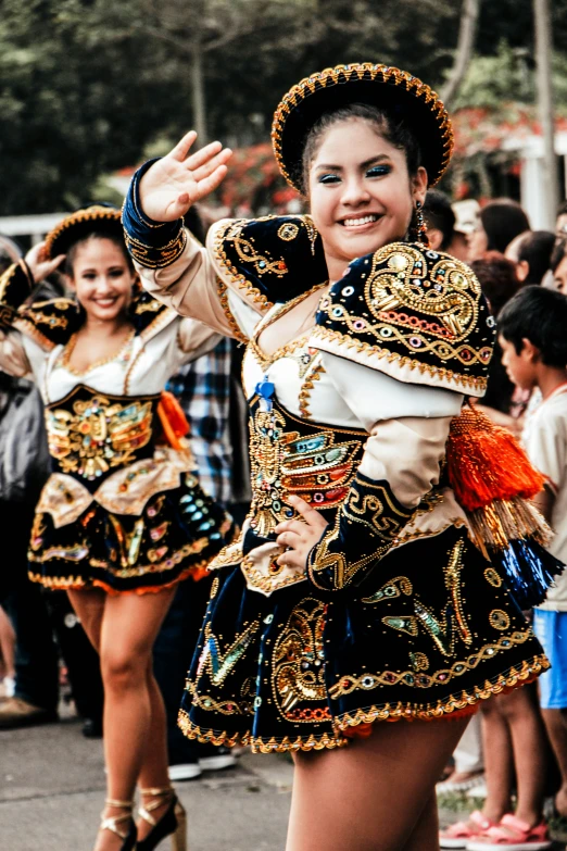 the women are wearing colorful costumes and holding hands up