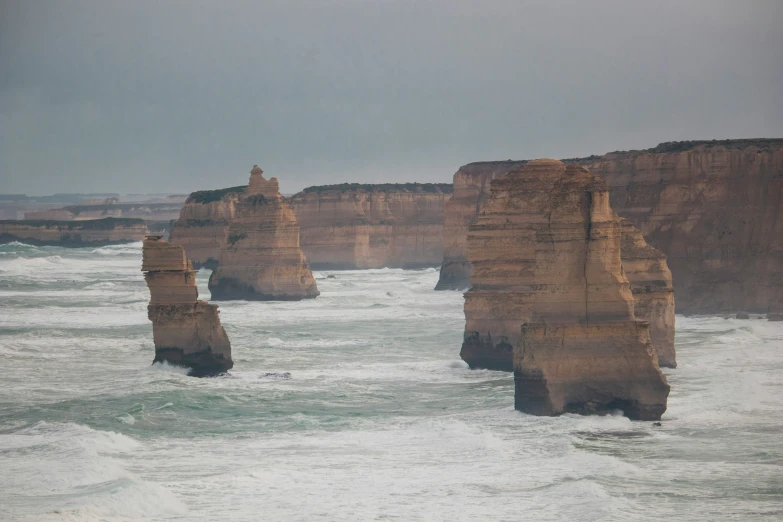 some very long stacks of rocks sticking out from the water