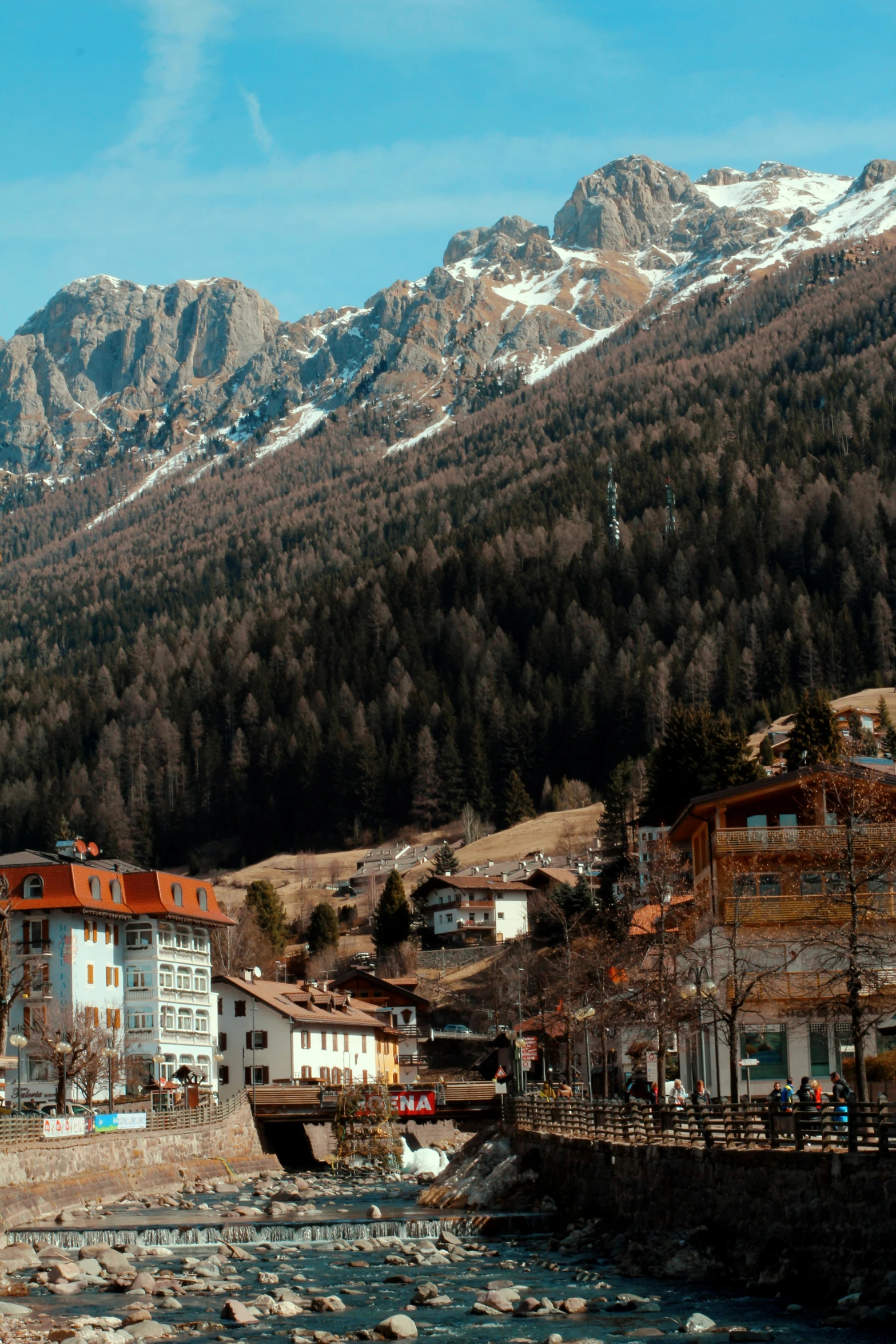 a group of houses sits near a river in front of the mountains