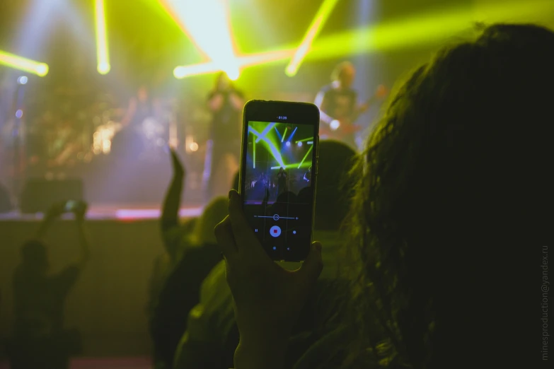 someone holding up their cell phone in front of some concert lights