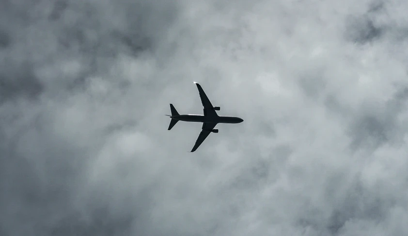 an airplane is flying against a gray cloudy sky