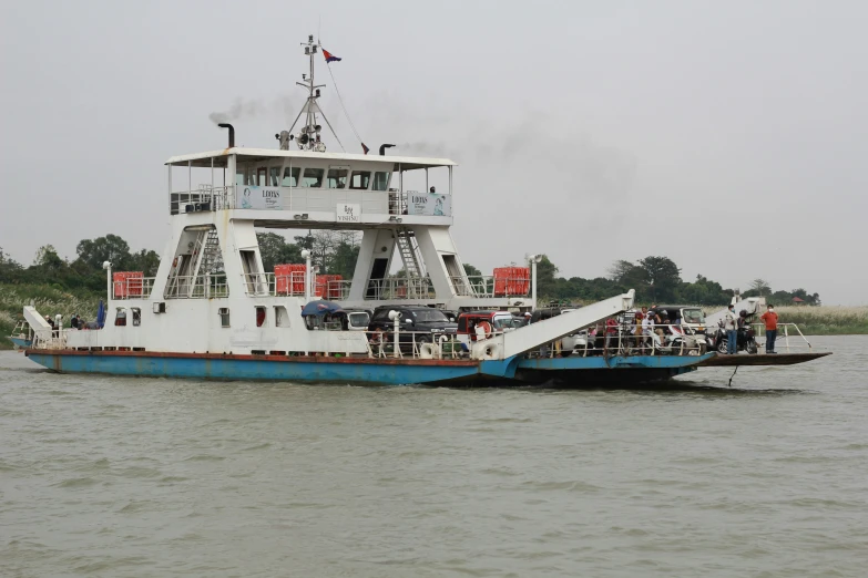 a large boat traveling across a river next to forest