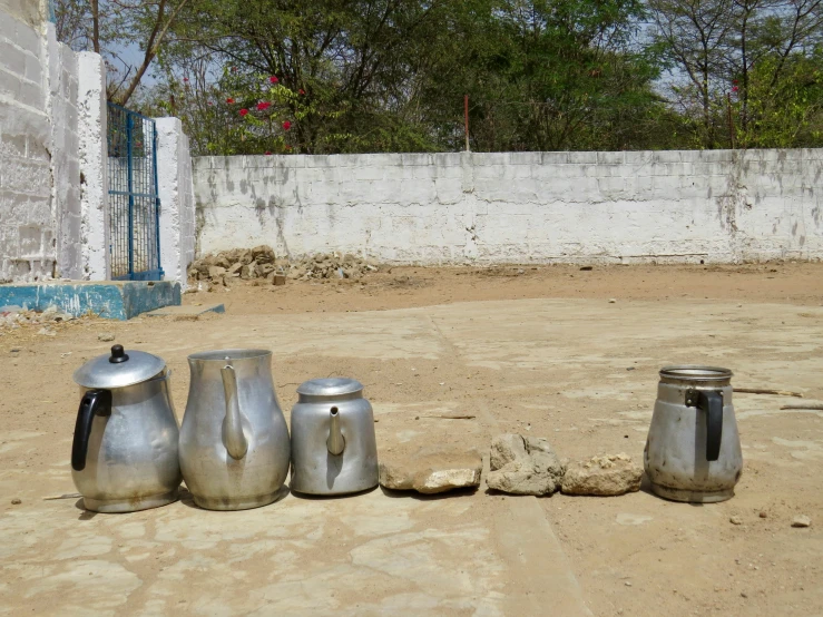 a couple of kettles and two cans sitting in the sand