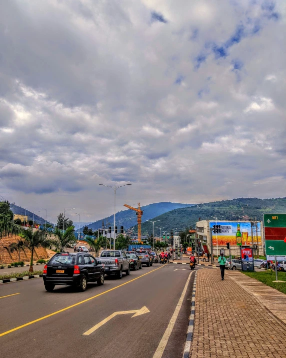 cars driving on road in a busy city with large mountain in background