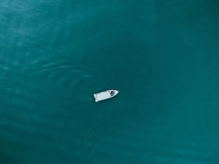 a small boat floating on top of a green ocean