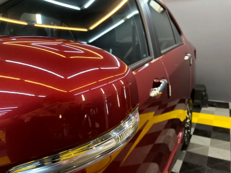 a shiny red car with yellow lines on the hood