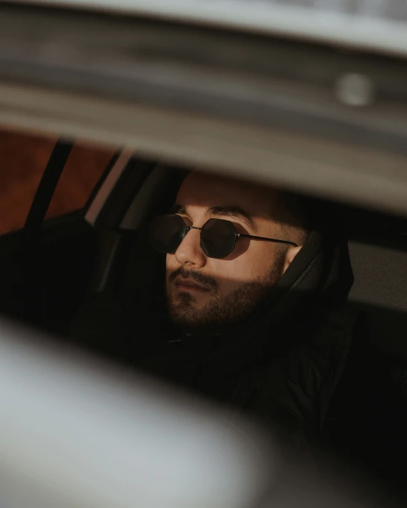 a man with sunglasses looking out the window of a car