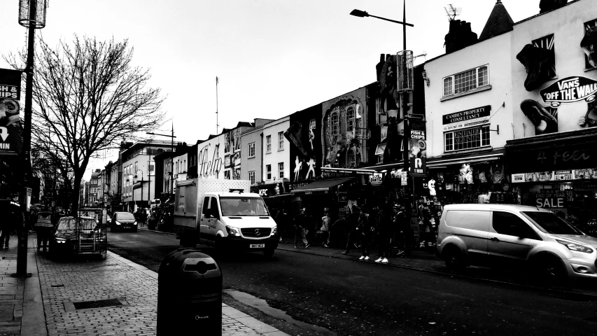 the road is lined with businesses with people and cars parked along both sides