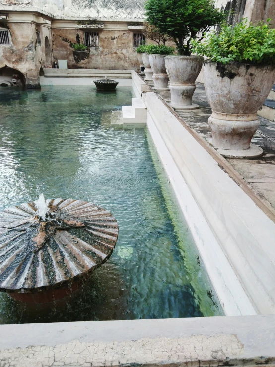 a large fountain with a spiral fountain spout, water spout and two urns in it
