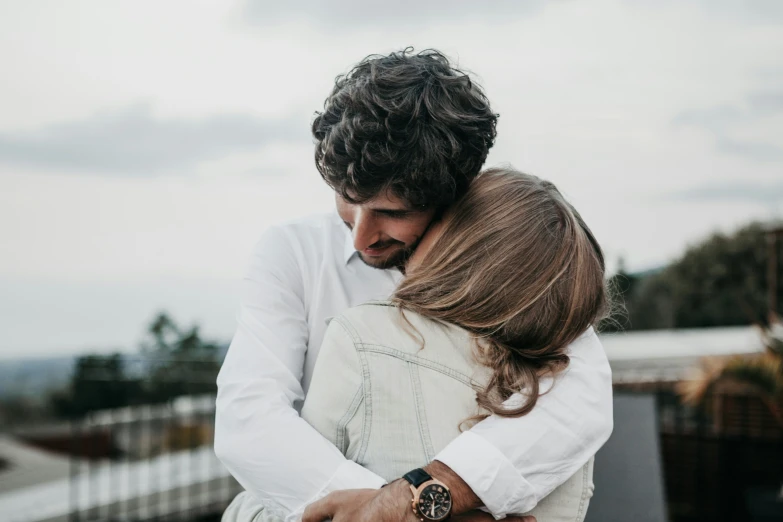 the young man is hugging the woman with long hair