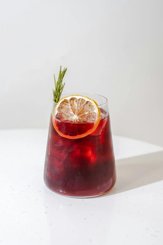 a glass filled with a red liquid sitting on top of a table