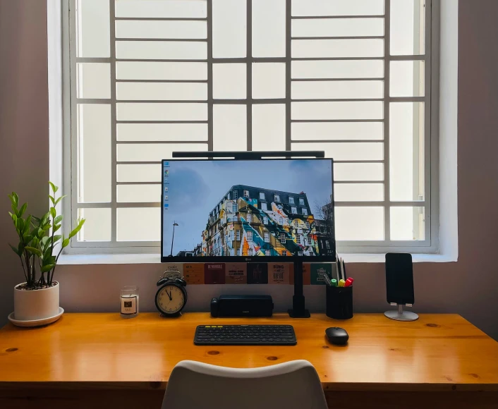 an imac, keyboard, and monitor on the table in a sunny room