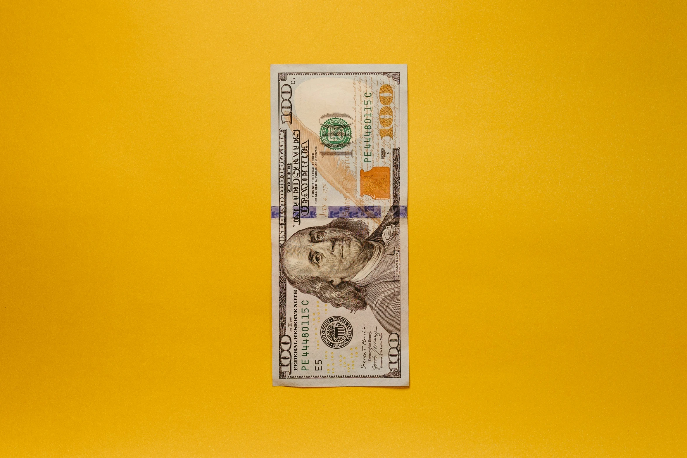 a one hundred dollar bill on a yellow background