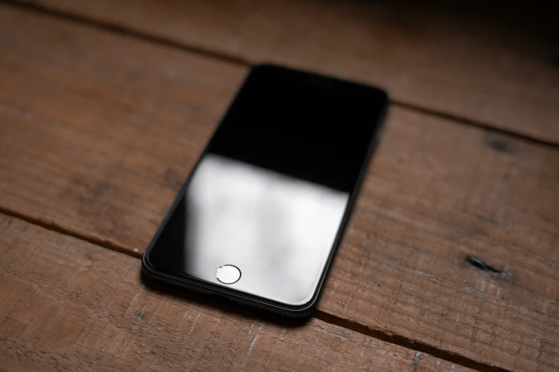 an iphone sits on the wooden table top