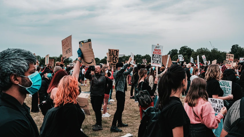 a large group of people standing around each other holding signs