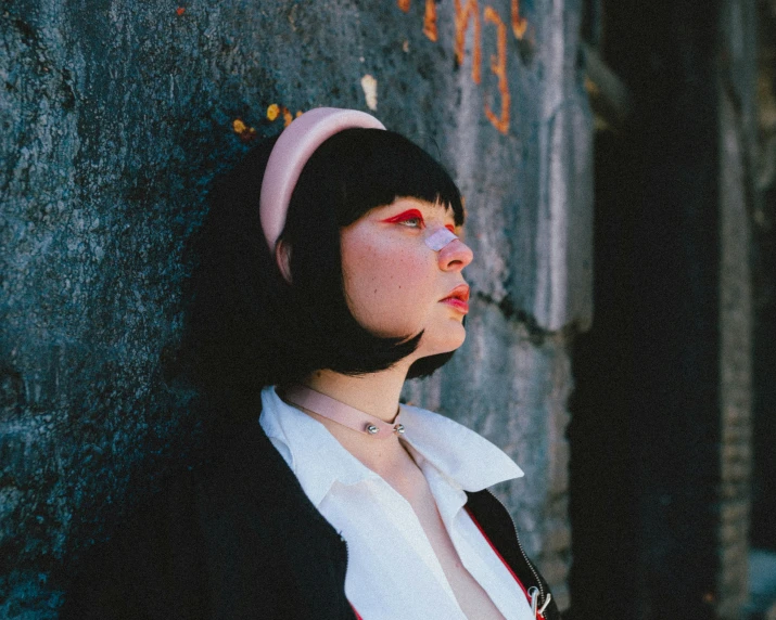 a woman leaning against a rock wearing an oversized black coat