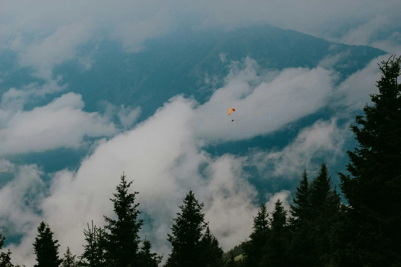 an orange kite flying through the clouds in the air