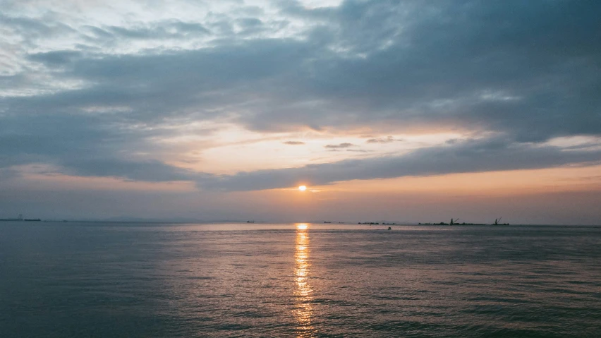 the sun is shining over the water off a large body of water