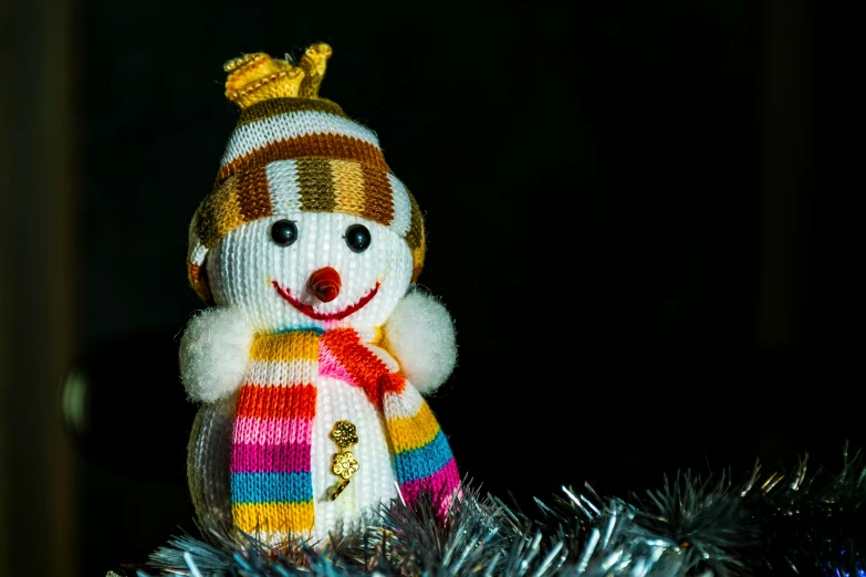 a snowman made out of colorful knitted material on top of a christmas tree