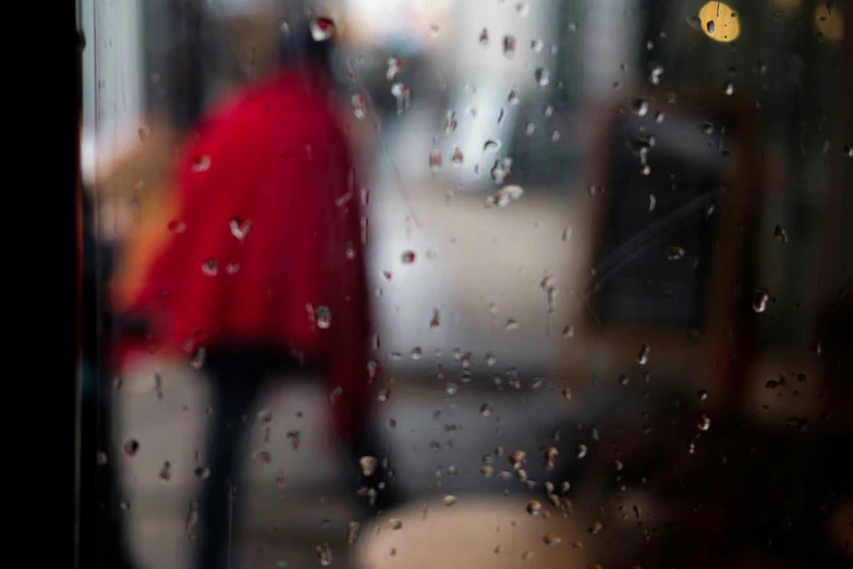 woman in red coat with umbrella looking out the window