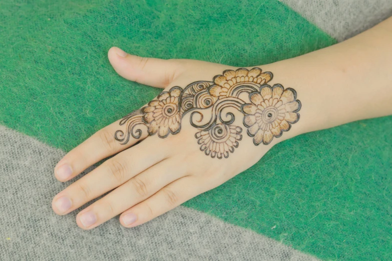 a henna design on a hand sitting on top of green cloth