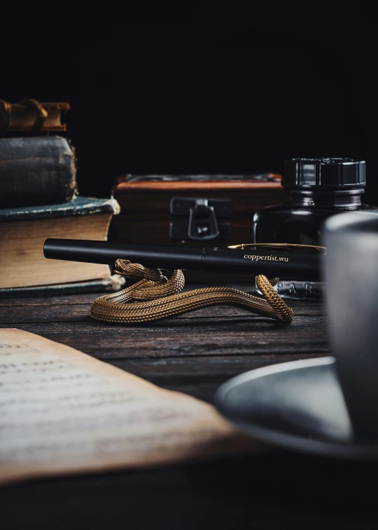 a stack of books, two pens and a pen next to an open book