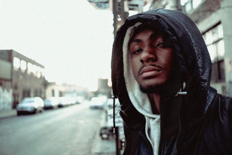 a man standing on the sidewalk and wearing a hoodie