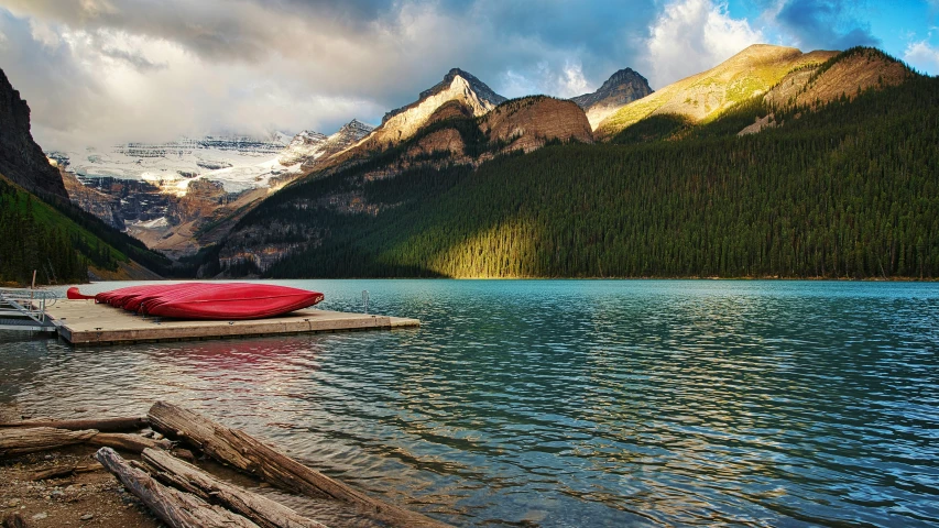 the red canoe sits on top of the dock near the mountains