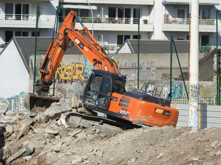 the large orange excavator is dumping dirt in front of a building