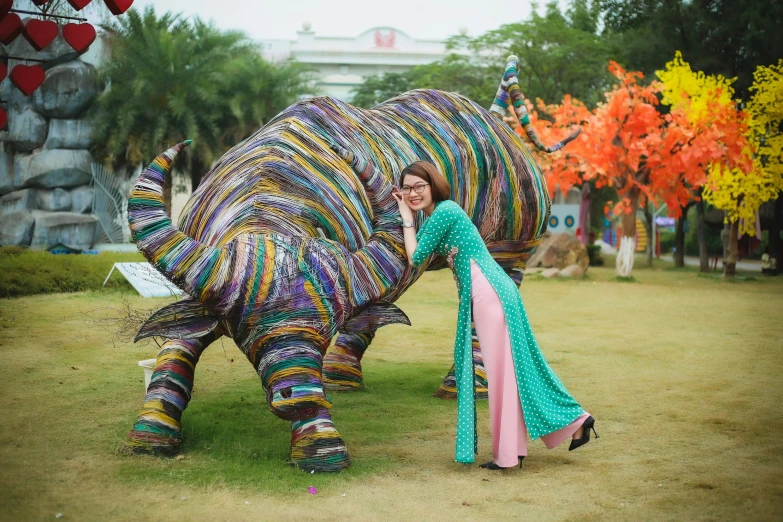 a woman poses in front of a large elephant sculpture