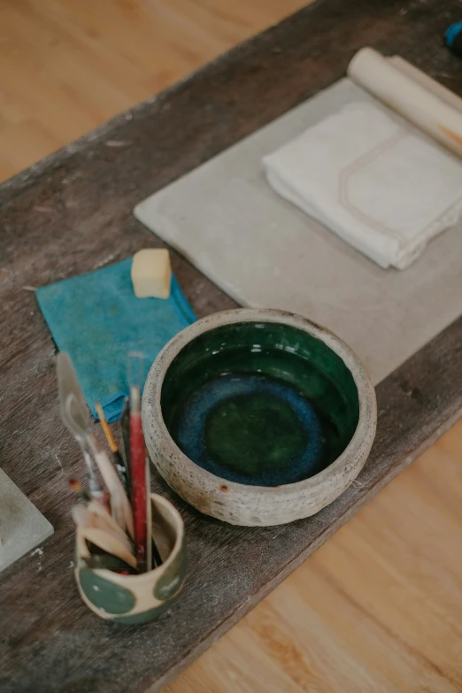 there is a bowl with some paint on it and another small bowl of scissors