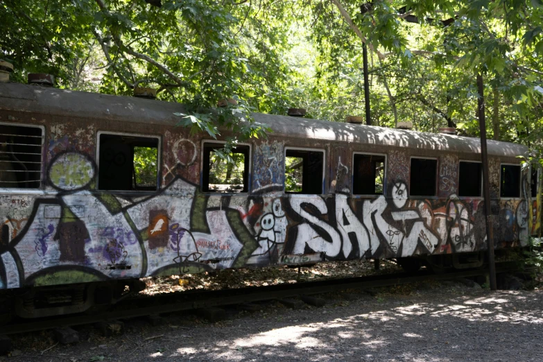 an old train covered with graffiti under some trees