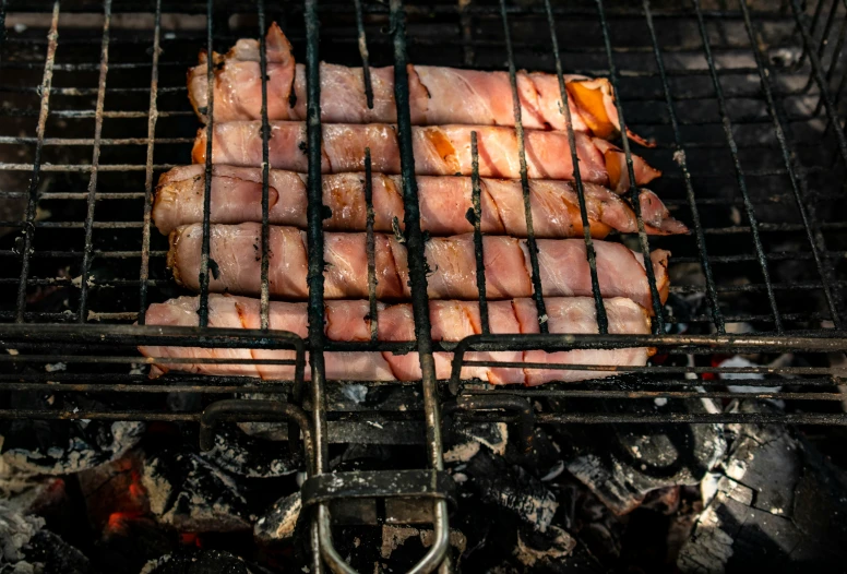 a grill has several pieces of ham cooking on it