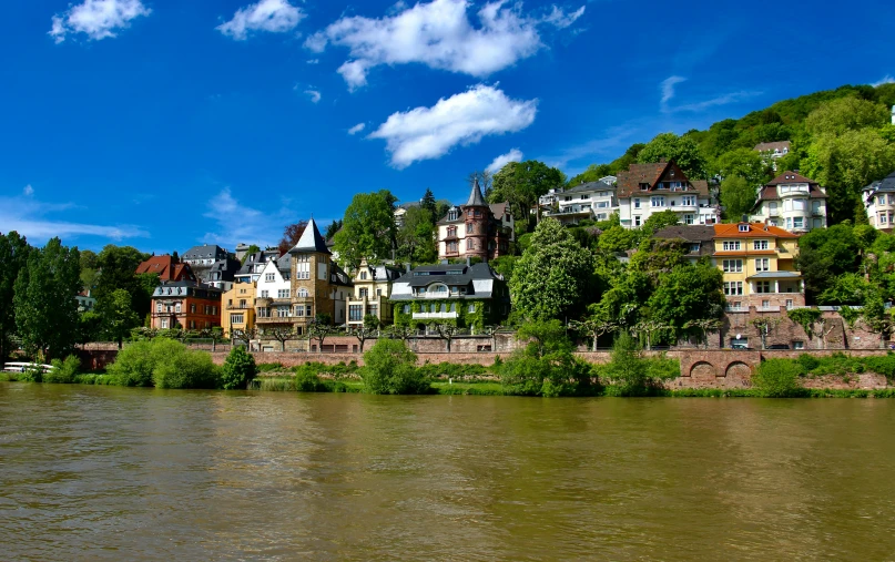 a town sits above the water near a bridge