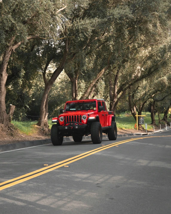 a red jeep is driving along a country road